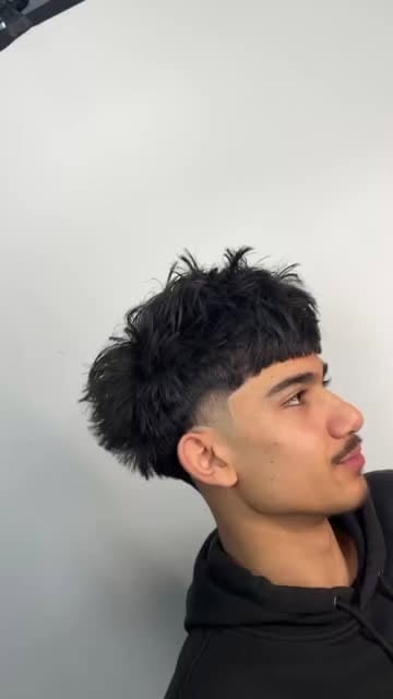 Side profile of a young man with short black textured hair and a fade